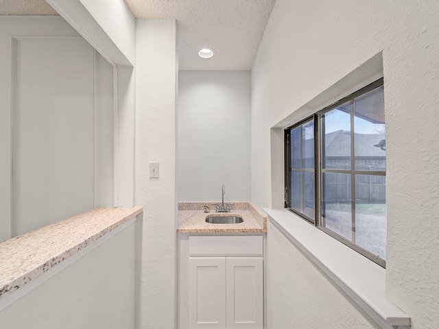 bathroom featuring vanity, a textured ceiling, and a healthy amount of sunlight