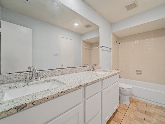 full bathroom featuring a textured ceiling, vanity, toilet, tiled shower / bath, and tile patterned floors