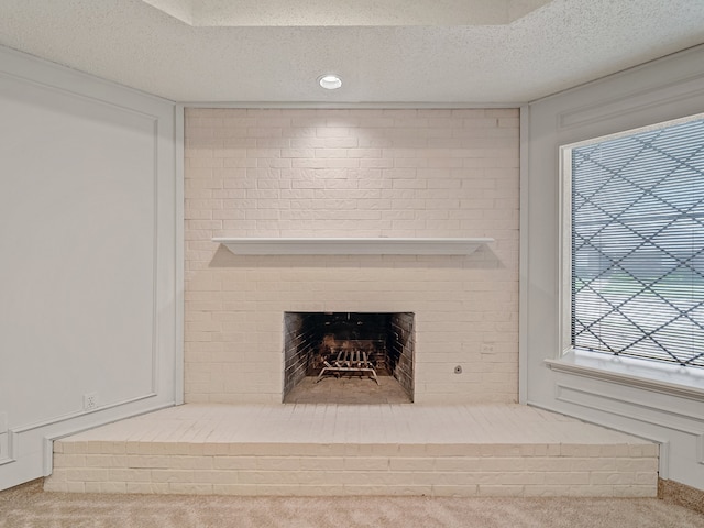 details with a textured ceiling, carpet flooring, and a brick fireplace