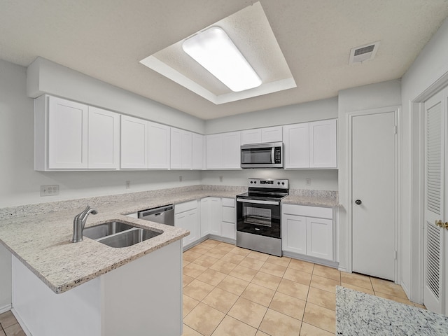 kitchen with stainless steel appliances, kitchen peninsula, and white cabinetry