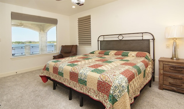 bedroom with light colored carpet and a water view