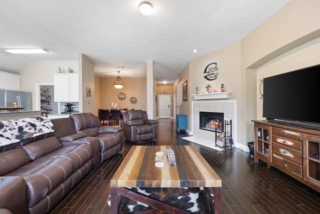 living room featuring lofted ceiling, a fireplace, dark hardwood / wood-style flooring, and a notable chandelier