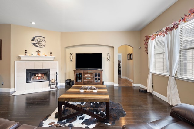 living room with a fireplace, dark wood-type flooring, and a healthy amount of sunlight