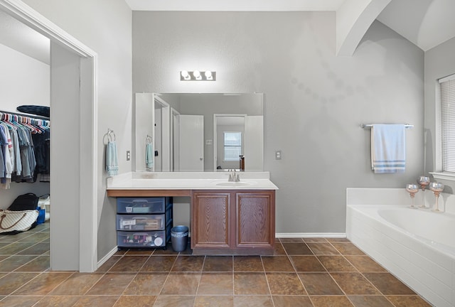 bathroom with a healthy amount of sunlight, tile patterned floors, a bath, and vanity