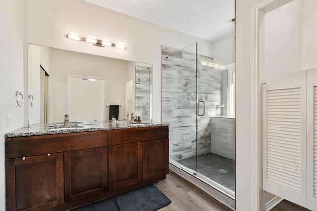 bathroom with hardwood / wood-style flooring, vanity, walk in shower, and a textured ceiling