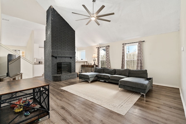 living room featuring hardwood / wood-style flooring, ceiling fan, lofted ceiling, and a fireplace