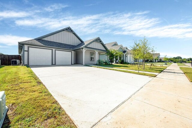 view of front of house featuring central AC unit, a front yard, and a garage