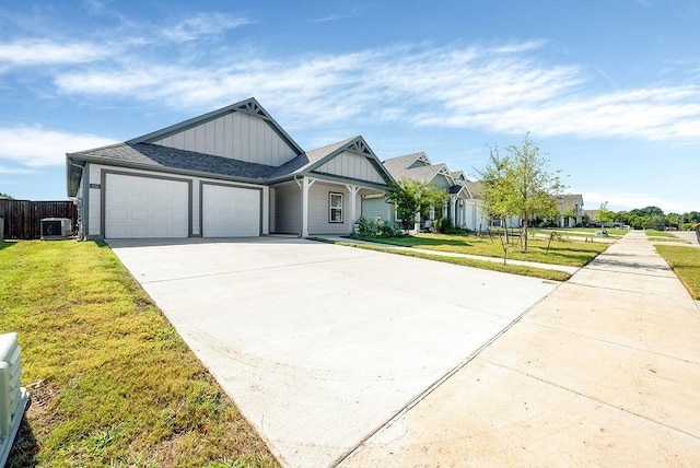 view of front facade with board and batten siding, a front yard, central AC unit, a garage, and concrete driveway
