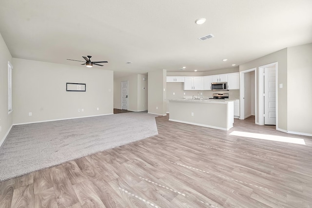 unfurnished living room featuring ceiling fan and light hardwood / wood-style flooring