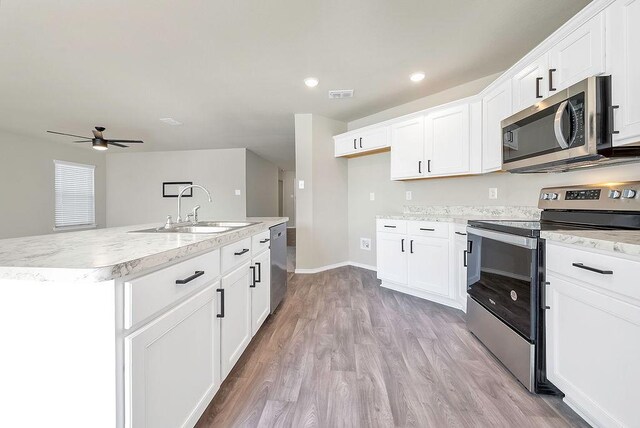 kitchen with appliances with stainless steel finishes, white cabinetry, ceiling fan, light hardwood / wood-style flooring, and sink