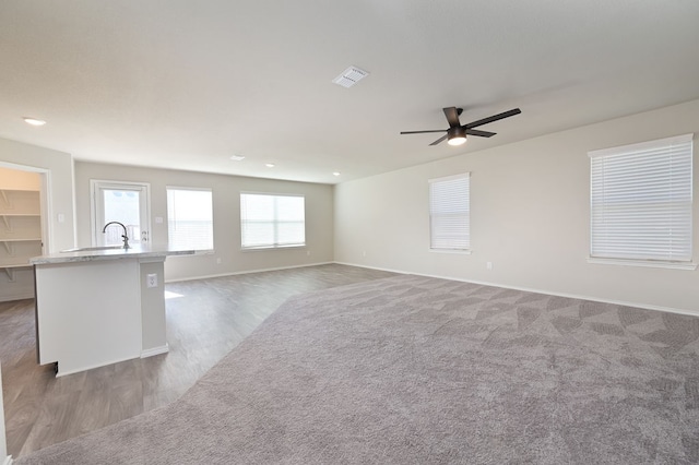 unfurnished living room with dark carpet and ceiling fan