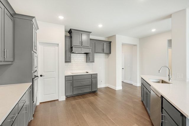 kitchen featuring light wood-type flooring, appliances with stainless steel finishes, gray cabinetry, and sink