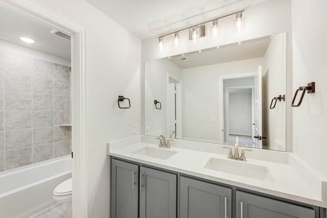 full bathroom with toilet, tile patterned flooring, tiled shower / bath, and vanity