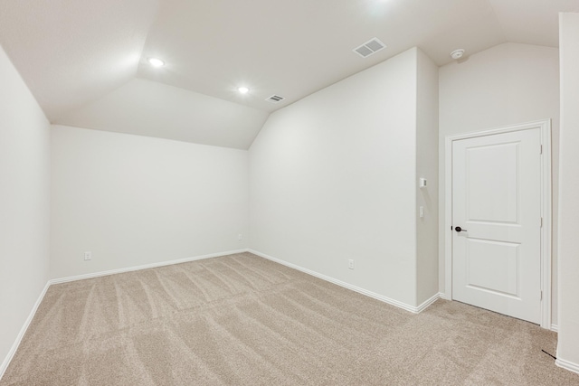 additional living space with light colored carpet and vaulted ceiling