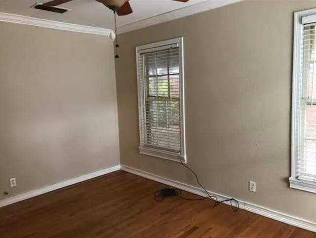 empty room featuring ornamental molding, dark wood-type flooring, a healthy amount of sunlight, and ceiling fan