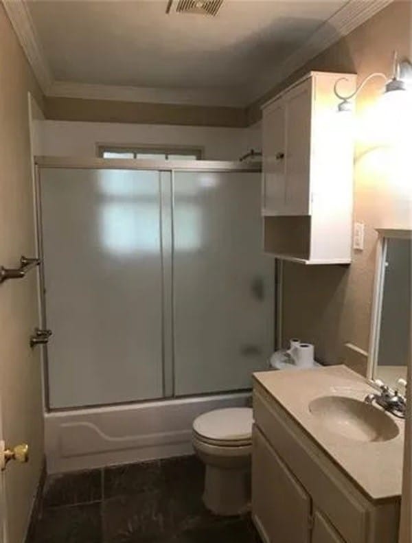 full bathroom with vanity, toilet, ornamental molding, and enclosed tub / shower combo