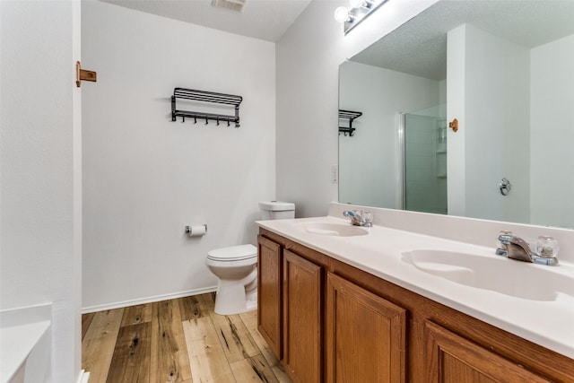 bathroom featuring vanity, a textured ceiling, a shower with door, wood-type flooring, and toilet