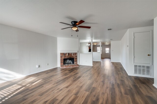 unfurnished living room with ceiling fan with notable chandelier, dark hardwood / wood-style flooring, and a fireplace