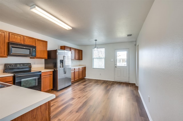 kitchen with black appliances, pendant lighting, and hardwood / wood-style floors