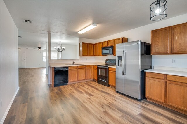 kitchen with sink, light hardwood / wood-style floors, decorative light fixtures, black appliances, and ceiling fan with notable chandelier