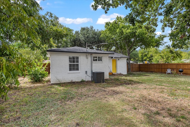 back of house with central air condition unit and a yard