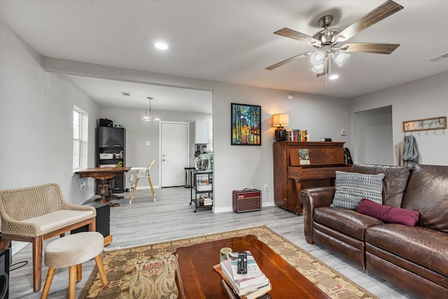 living room featuring light wood-type flooring and ceiling fan with notable chandelier