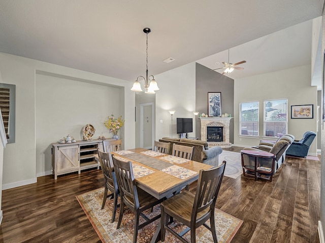 dining space with visible vents, baseboards, lofted ceiling, dark wood-style floors, and a brick fireplace