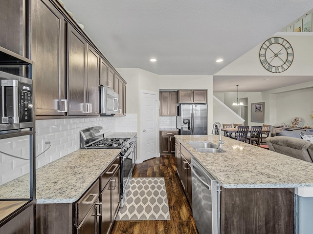 kitchen with sink, tasteful backsplash, dark brown cabinets, hanging light fixtures, and appliances with stainless steel finishes