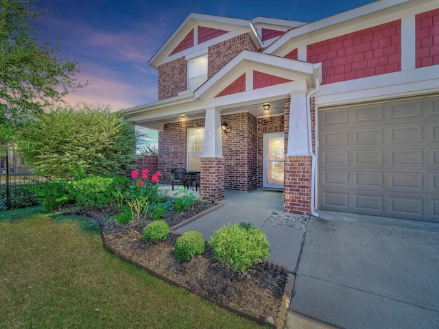 exterior entry at dusk featuring a garage, a yard, and a porch