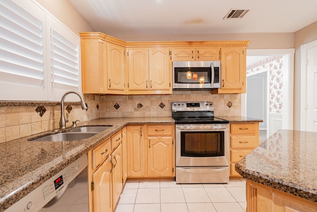 kitchen with sink, light stone countertops, appliances with stainless steel finishes, and light brown cabinets