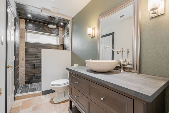 bathroom with vanity, toilet, and a tile shower