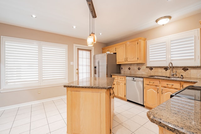 kitchen with light brown cabinetry, hanging light fixtures, a center island, light stone countertops, and stainless steel appliances