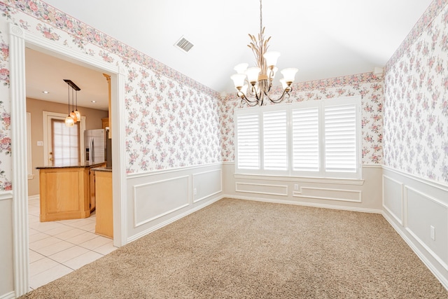 carpeted spare room featuring an inviting chandelier