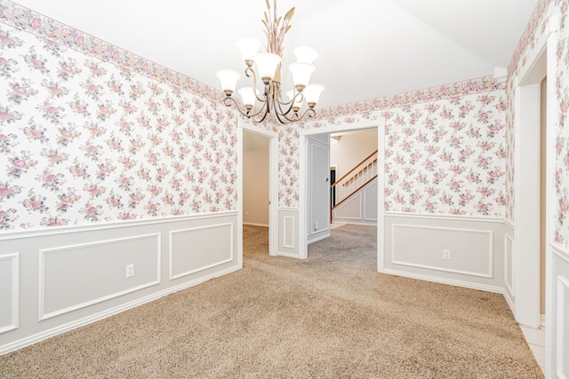 spare room with lofted ceiling, carpet flooring, and an inviting chandelier