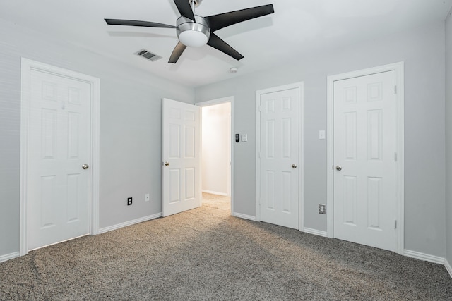 unfurnished bedroom with carpet flooring, ceiling fan, and multiple closets