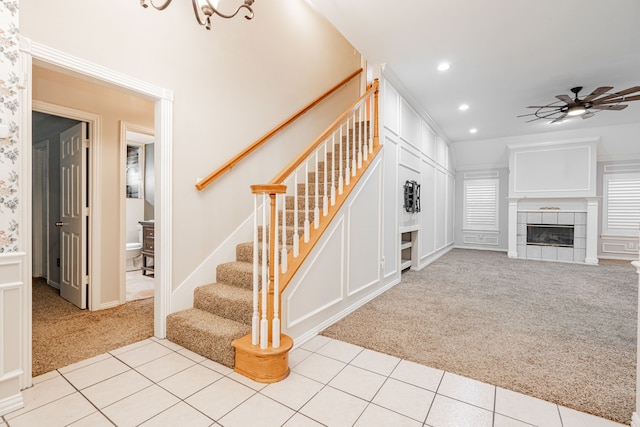 interior space featuring light colored carpet, ceiling fan, and a tiled fireplace