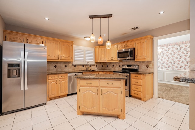 kitchen with a center island, decorative light fixtures, stainless steel appliances, sink, and dark stone counters