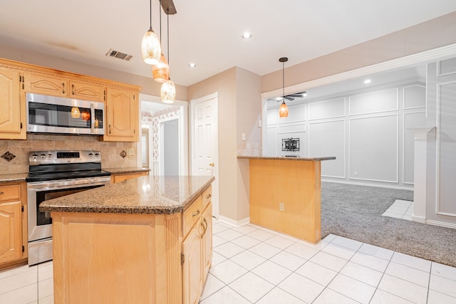 kitchen featuring light stone countertops, a kitchen island, stainless steel appliances, and decorative backsplash