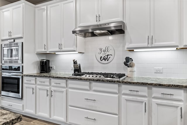 kitchen featuring white cabinets, dark stone counters, decorative backsplash, and appliances with stainless steel finishes