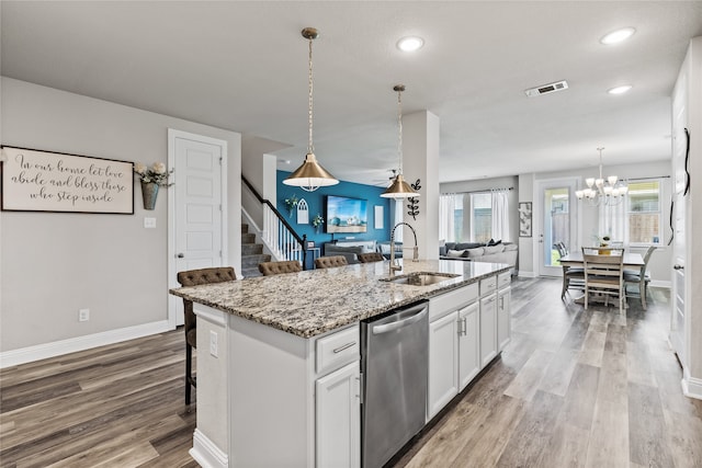 kitchen featuring white cabinetry, sink, a breakfast bar, a kitchen island with sink, and dishwasher