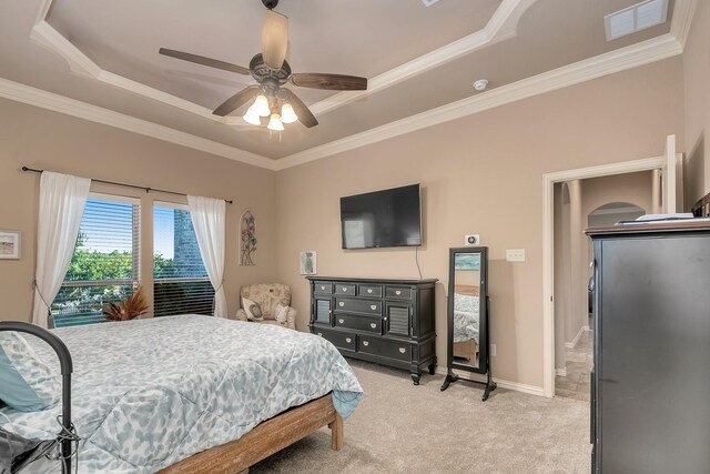 bedroom featuring crown molding, ceiling fan, a tray ceiling, and light colored carpet