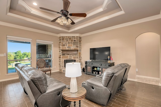 living room with wood-type flooring, a tray ceiling, crown molding, and ceiling fan