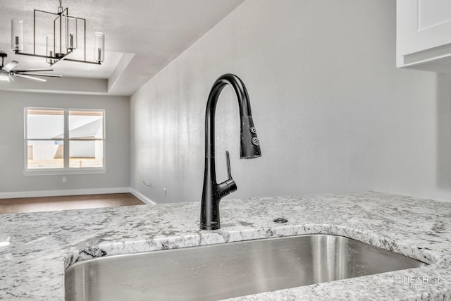 room details featuring light stone counters, sink, and ceiling fan