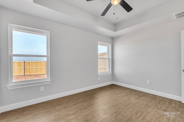 unfurnished room with ceiling fan, hardwood / wood-style flooring, and a raised ceiling