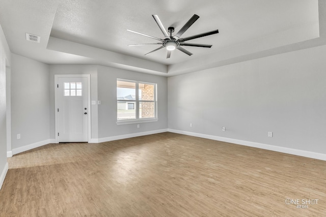 entrance foyer featuring light hardwood / wood-style floors, a raised ceiling, a textured ceiling, and ceiling fan