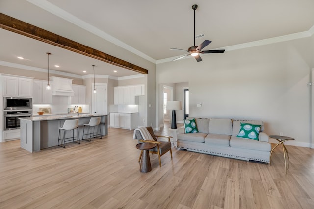 living room with ornamental molding, light wood-type flooring, ceiling fan, and sink