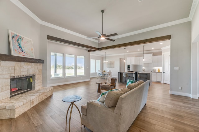 living room with a stone fireplace, ornamental molding, ceiling fan, and light hardwood / wood-style flooring