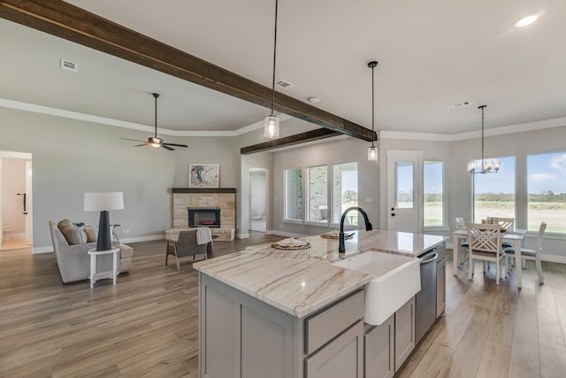 kitchen featuring light stone counters, light hardwood / wood-style floors, plenty of natural light, and a stone fireplace