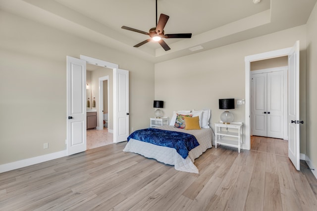 bedroom with light hardwood / wood-style flooring, ceiling fan, and a raised ceiling