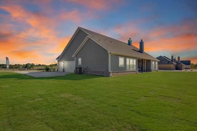 back house at dusk featuring cooling unit and a yard